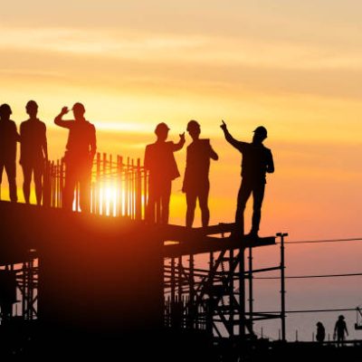 Silhouette of Engineer and worker team on building site, Industrial sector construction site at sunset in evening time